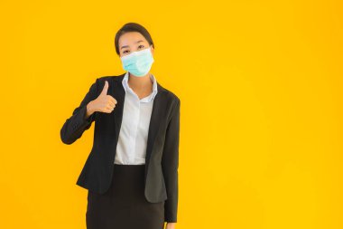 Güzel genç iş kadını portresi Korunmak için maske takıyor 19 koronavirüs sarı izole arka planda