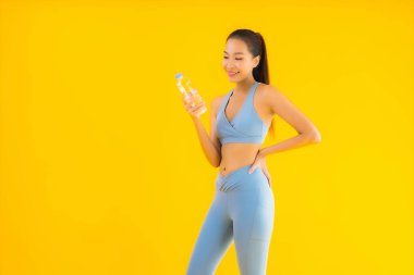 Sarı izole edilmiş arka planda su şişesiyle güzel bir Asyalı kadın portresi.