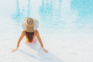 Güzel bir Asyalı kadın portresi. Tatil gezisinde deniz manzaralı açık havuz etrafında rahatça yüzebiliyor.