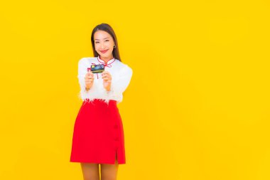 Sarı arka planda online alışveriş için kredi kartı olan güzel bir Asyalı kadın portresi.