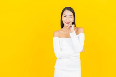 Portre güzel genç iş kadını gülümseyen ve eylem sarı arka planlı Asyalı kadın