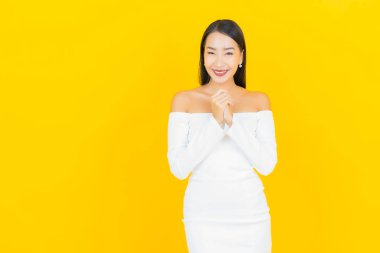 Portre güzel genç iş kadını gülümseyen ve eylem sarı arka planlı Asyalı kadın