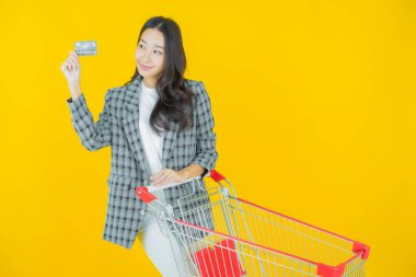 Renkli arka planda süpermarketten alınmış market sepetiyle gülümseyen güzel Asyalı kadın portresi.