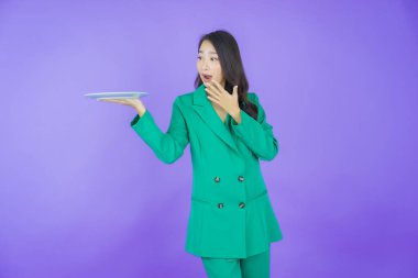 Güzel Asyalı bir kadının portresi. Arka planda boş tabak tabağıyla gülümsüyor.