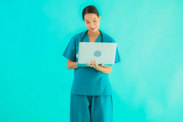 Portrait beautiful young asian doctor woman with laptop or computer on blue isolated background