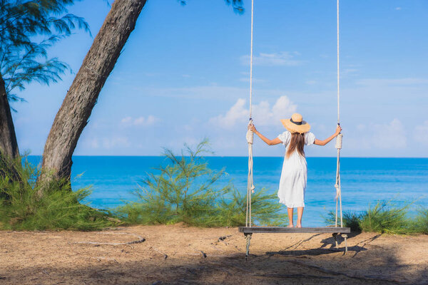 Портрет красивая молодая азиатская женщина расслабиться улыбка на качелях вокруг пляжа море океан для путешествия на природу в отпуск