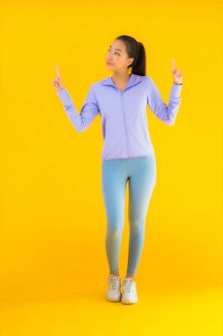 Sarı izole edilmiş arka planda spor giysili güzel Asyalı kadın portresi egzersize hazır.