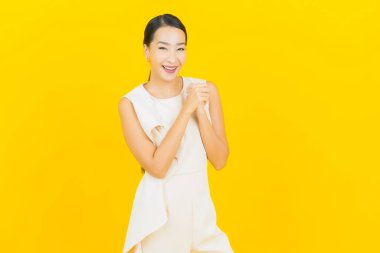 Asyalı güzel bir kadının portresi. Sarı arka planda hareketli gülümsüyor.