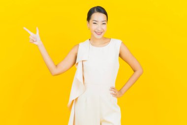 Asyalı güzel bir kadının portresi. Sarı arka planda hareketli gülümsüyor.