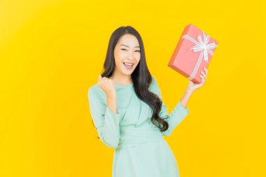 Güzel bir Asyalı kadının portresi. Arka planda kırmızı hediye kutusuyla gülümsüyor.