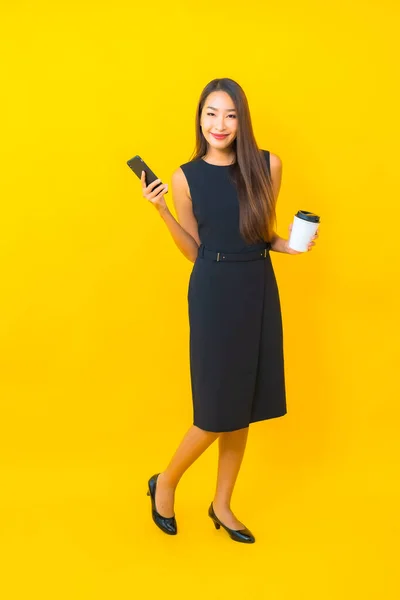 Kahve Fincanı Sarı Arka Planda Akıllı Cep Telefonlu Güzel Asyalı — Stok fotoğraf