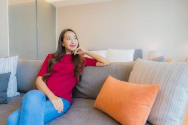 Güzel bir Asyalı kadın portresi. Yatak odasındaki kanepede rahatla. Gülümse.