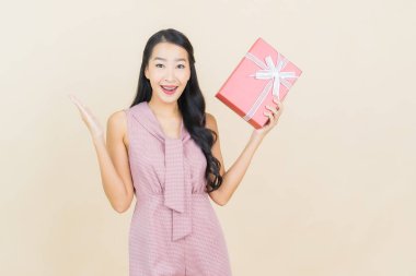 Güzel bir Asyalı kadının portresi. Arka planda kırmızı hediye kutusuyla gülümsüyor.