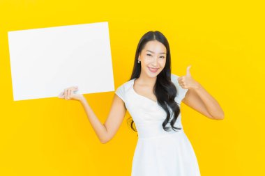 Sarı arka planda boş beyaz ilan panosu olan güzel Asyalı kadın portresi