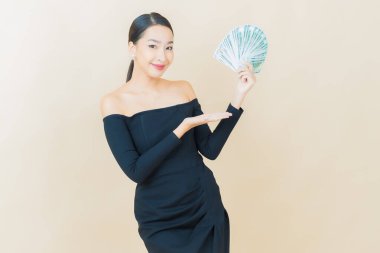 Asyalı güzel bir kadının portresi. Renkli arka planda bol para ve parayla gülümsüyor.