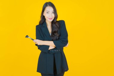 Renk arka planında makyaj fırçası olan güzel Asyalı kadın portresi.