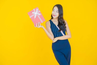 Güzel bir Asyalı kadının portresi. Arka planda kırmızı hediye kutusuyla gülümsüyor.