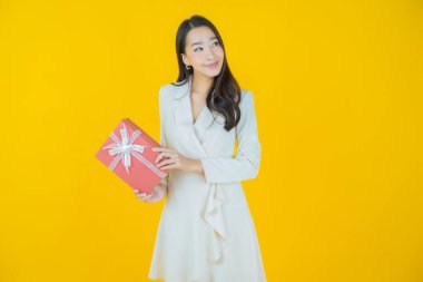 Güzel bir Asyalı kadının portresi. Arka planda kırmızı hediye kutusuyla gülümsüyor.