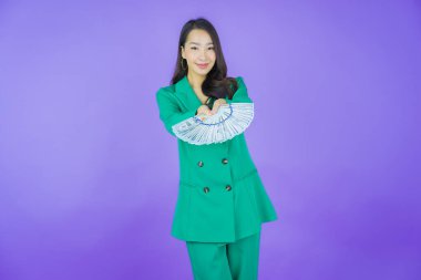 Asyalı güzel bir kadının portresi. Renkli arka planda bol para ve parayla gülümsüyor.