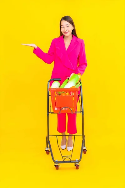 色彩艳丽的年轻亚洲女人 提着篮子 购物车和超级市场的杂货 — 图库照片