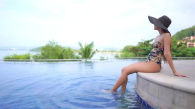 Otelde yüzme havuzunda dinlenen Asyalı güzel bir kadının görüntüsü.