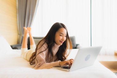 Yatak odasının iç kısmında dizüstü bilgisayar kullanan güzel Asyalı kadın portresi.