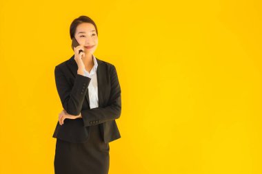 Portre güzel genç Asyalı kadın akıllı cep telefonu ve kahve fincanı ile izole edilmiş sarı arka planda