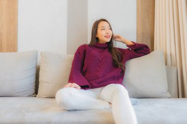 Portre güzel Asyalı kadın gülümsemesi. Oturma odasındaki kanepede rahatla.