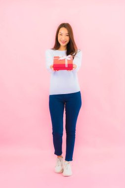 Portrait beautiful young asian woman with red gift box on pink isolated background
