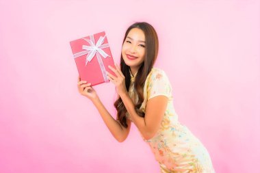 Pembe arka planda kırmızı hediye kutusu olan güzel bir Asyalı kadın portresi.