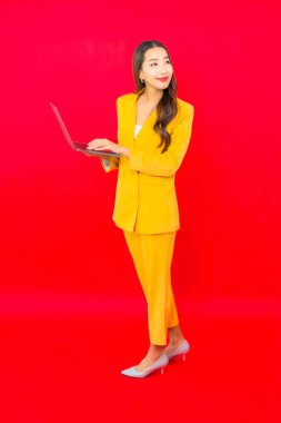 Portre güzel genç iş kadını Asyalı kadın kırmızı arka planda bilgisayar bilgisayarı kullanıyor