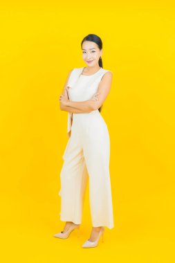 Asyalı güzel bir kadının portresi. Sarı arka planda hareketli gülümsüyor.