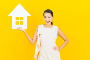 Sarı arka planda ev ya da kağıt tabelalı güzel Asyalı kadın portresi