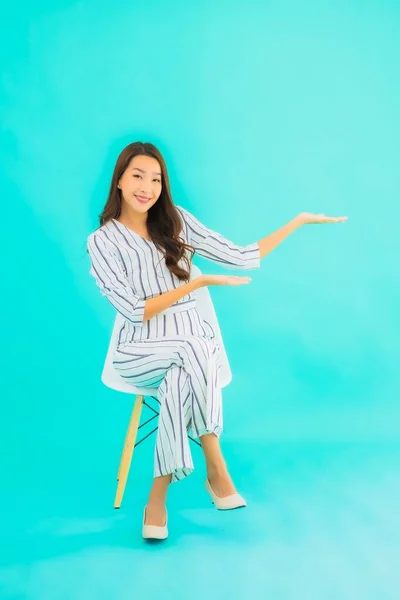 肖像画美しい若いアジアの女性の笑顔と椅子に座っている青隔離された背景 — ストック写真