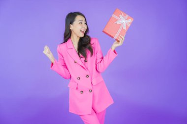 Güzel bir Asyalı kadının portresi. Arka planda kırmızı hediye kutusuyla gülümsüyor.