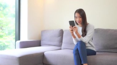 Güzel Asyalı kadının evde akıllı telefon kullandığının görüntüleri.