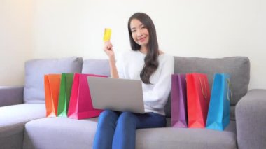 Renkli kağıt torbalarla karantina sırasında evde e-alışveriş yapan Asyalı güzel bir kadının görüntüleri.