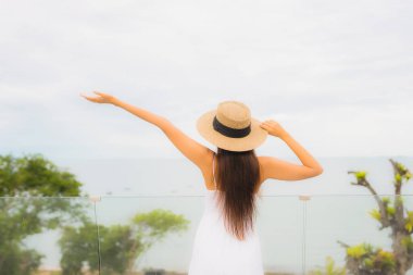 Portriat güzel genç Asyalı kadın deniz manzaralı balkonda mutlu bir gülümseme