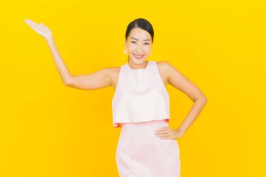 Asyalı güzel bir kadının portresi. Sarı arka planda hareketli gülümsüyor.