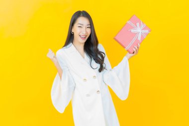 Güzel bir Asyalı kadının portresi. Arka planda kırmızı hediye kutusuyla gülümsüyor.