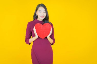 Portre güzel Asyalı genç kadın gülümsüyor kalp yastığı şeklinde renk arkaplan