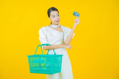 Renkli arka planda süpermarketten alınmış market sepetiyle gülümseyen güzel Asyalı kadın portresi.