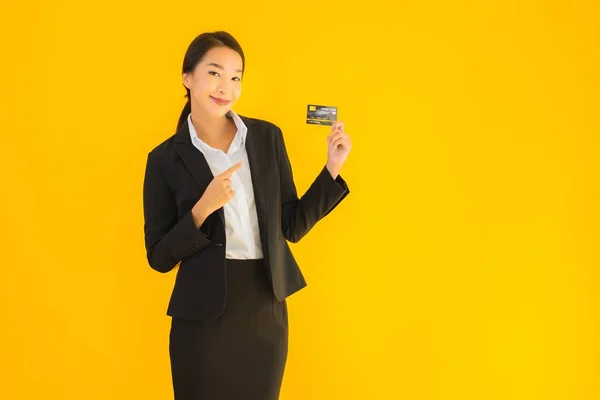 Portrait beautiful young business asian woman with credit card on yellow isolated background