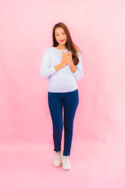 Portrait beautiful young asian woman smile with action on pink isolated background