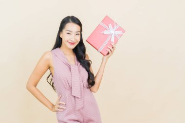 Güzel bir Asyalı kadının portresi. Arka planda kırmızı hediye kutusuyla gülümsüyor.