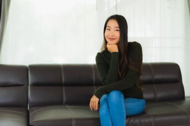 Güzel bir portre. Genç Asyalı kadın. Oturma odasındaki kanepede rahatla.