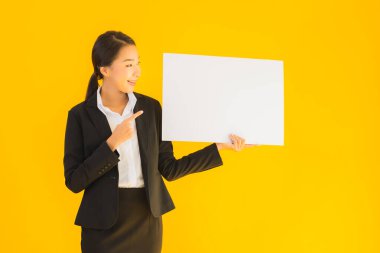 Güzel bir portre. Genç Asyalı kadın, sarı izole edilmiş arka planda boş beyaz tahta gösteriyor.