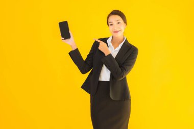 Portre güzel genç Asyalı kadın akıllı cep telefonu ve kahve fincanı ile izole edilmiş sarı arka planda