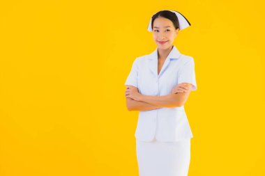 Güzel Asyalı genç Taylandlı hemşirenin portresi klinikteki ve hastanedeki hastalar için sarı izole edilmiş arka planda birçok eylem çalışmasında yer alıyor.