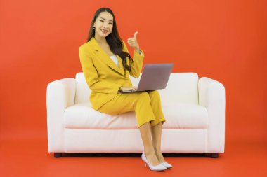 Güzel bir Asyalı kadın portresi kırmızı arka planda bilgisayar bilgisayarı kullanıyor.